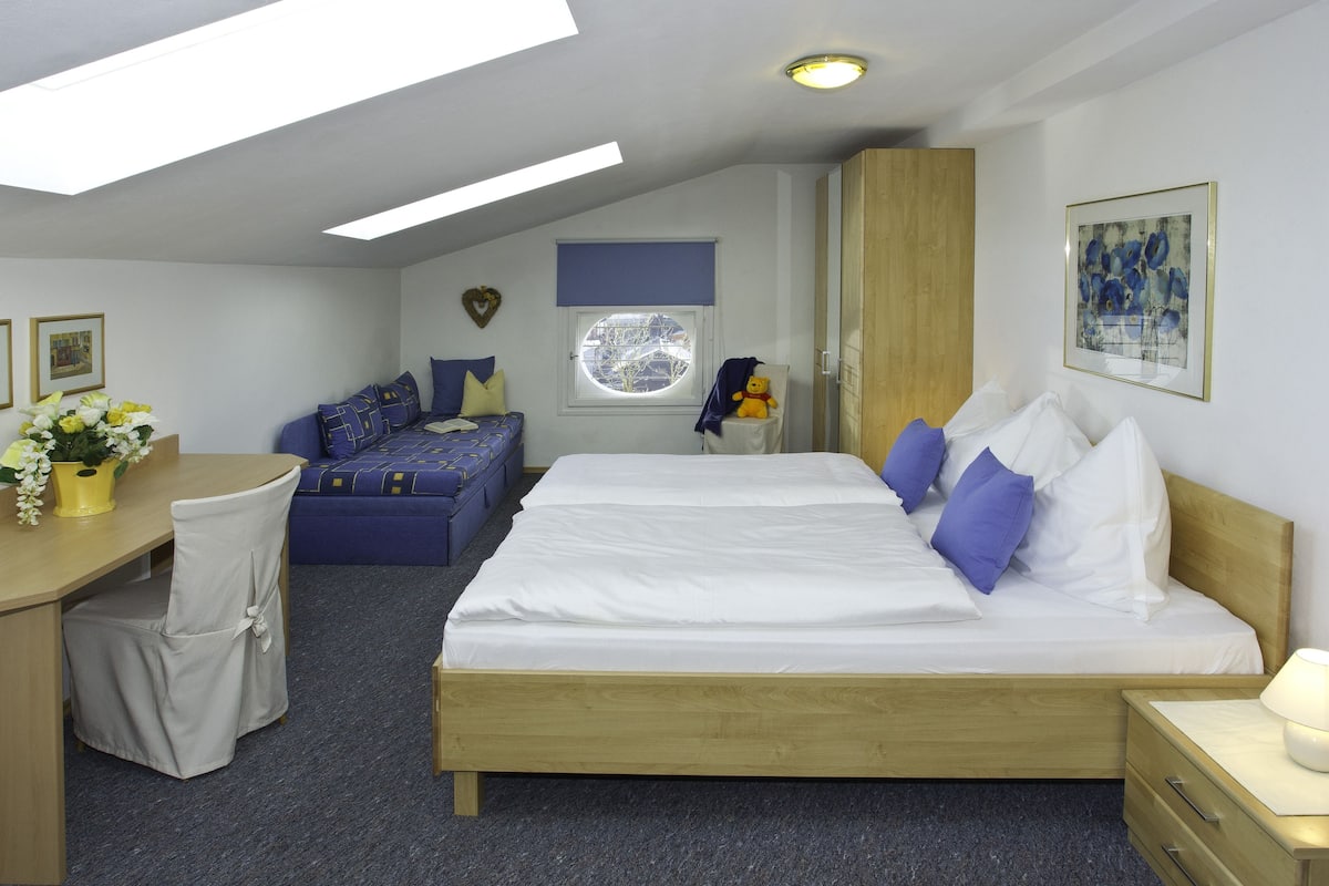 Une chambre à coucher comprenant un lit, un bureau, une chaise, une armoire et une fenêtre.