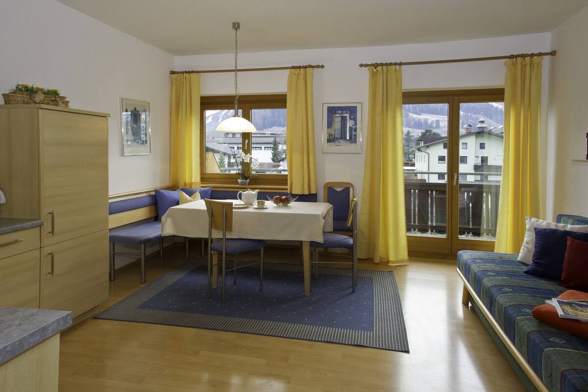 Une pièce comprenant une table à manger, des chaises, un canapé et offrant une vue sur une montagne.