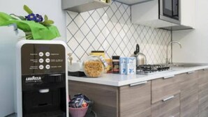 A modern kitchen with a built-in coffee machine, a gas stove, and a microwave. - CAPRI B&B (Salerno)