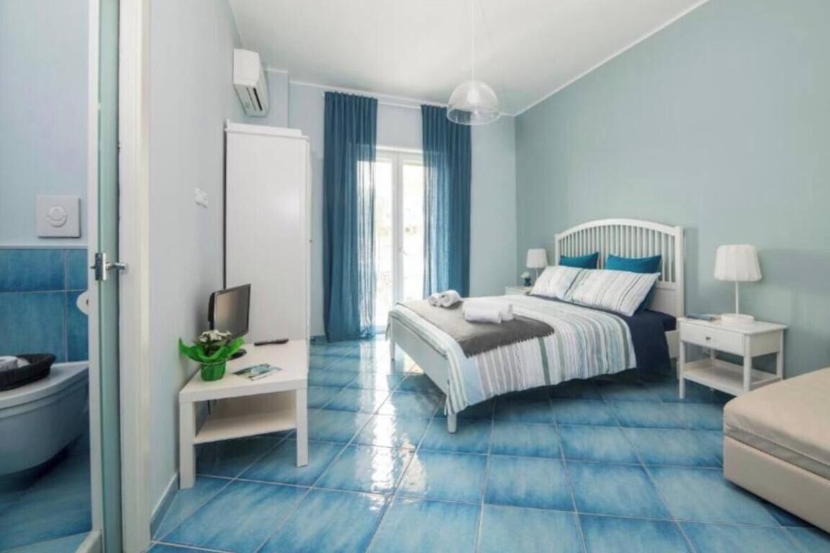 Ein Schlafzimmer mit Bett, Nachttischen, einem Sessel und einem Badezimmer mit Toilette und Waschbecken.