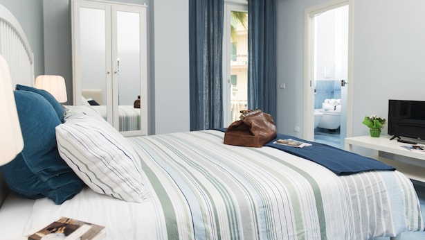 A hotel room with a bed, a desk, a TV, and a window with curtains. - CAPRI B&B (Salerno)