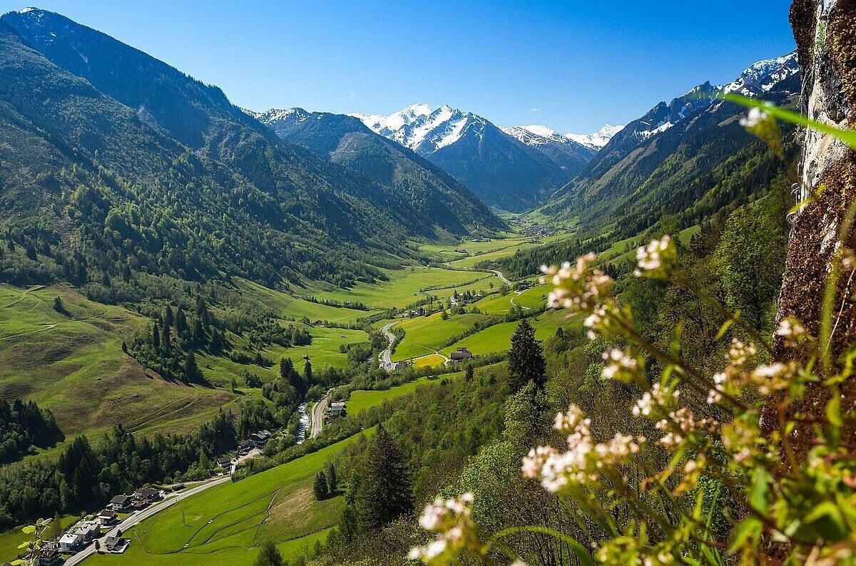 Eine Berglandschaft mit Tal, Häusern und einer Straße.