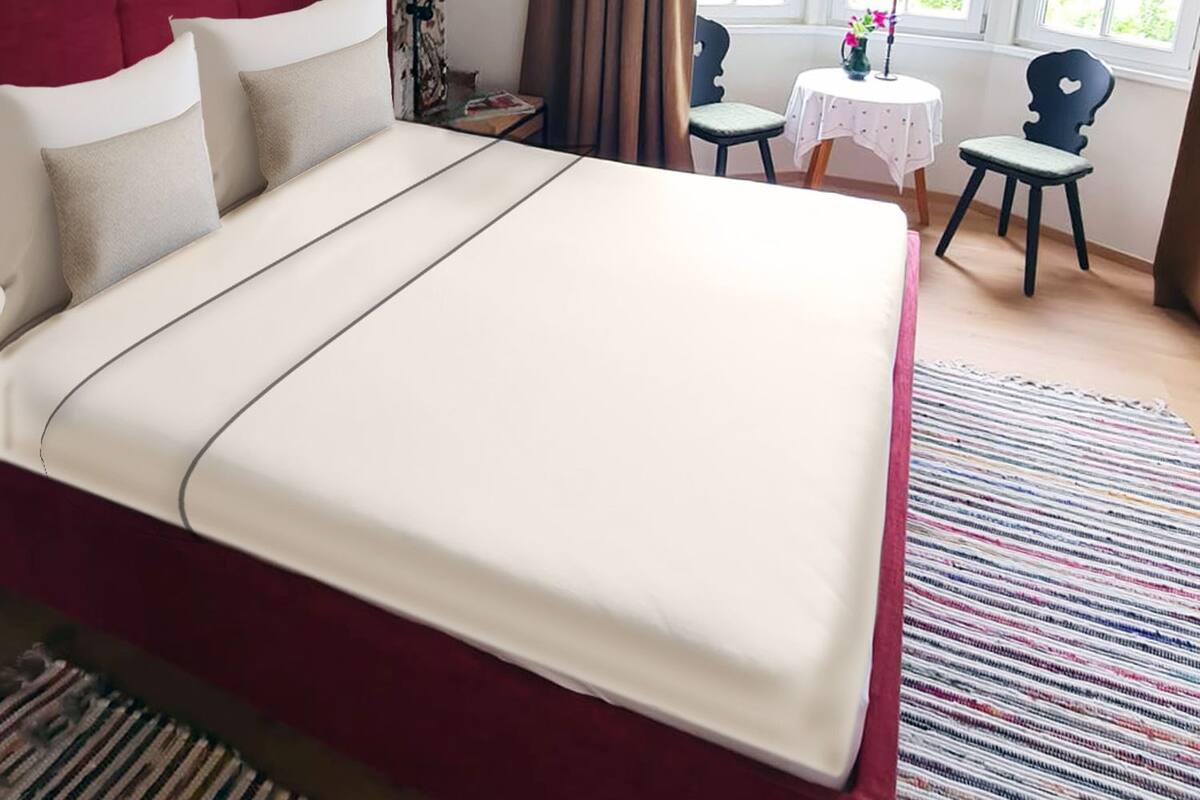 A bedroom with a large bed, a desk, and a chair near a window.