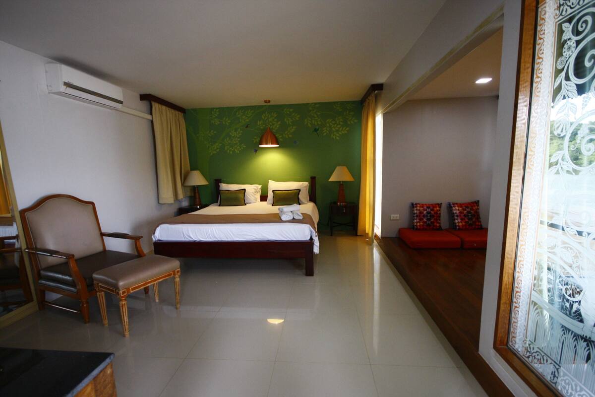 A hotel room with a bed, a chair, a sofa, and a table.