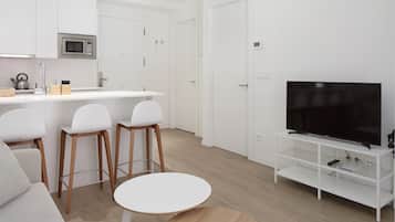 A modern kitchen with white cabinets, a microwave, and a bar area with stools.
