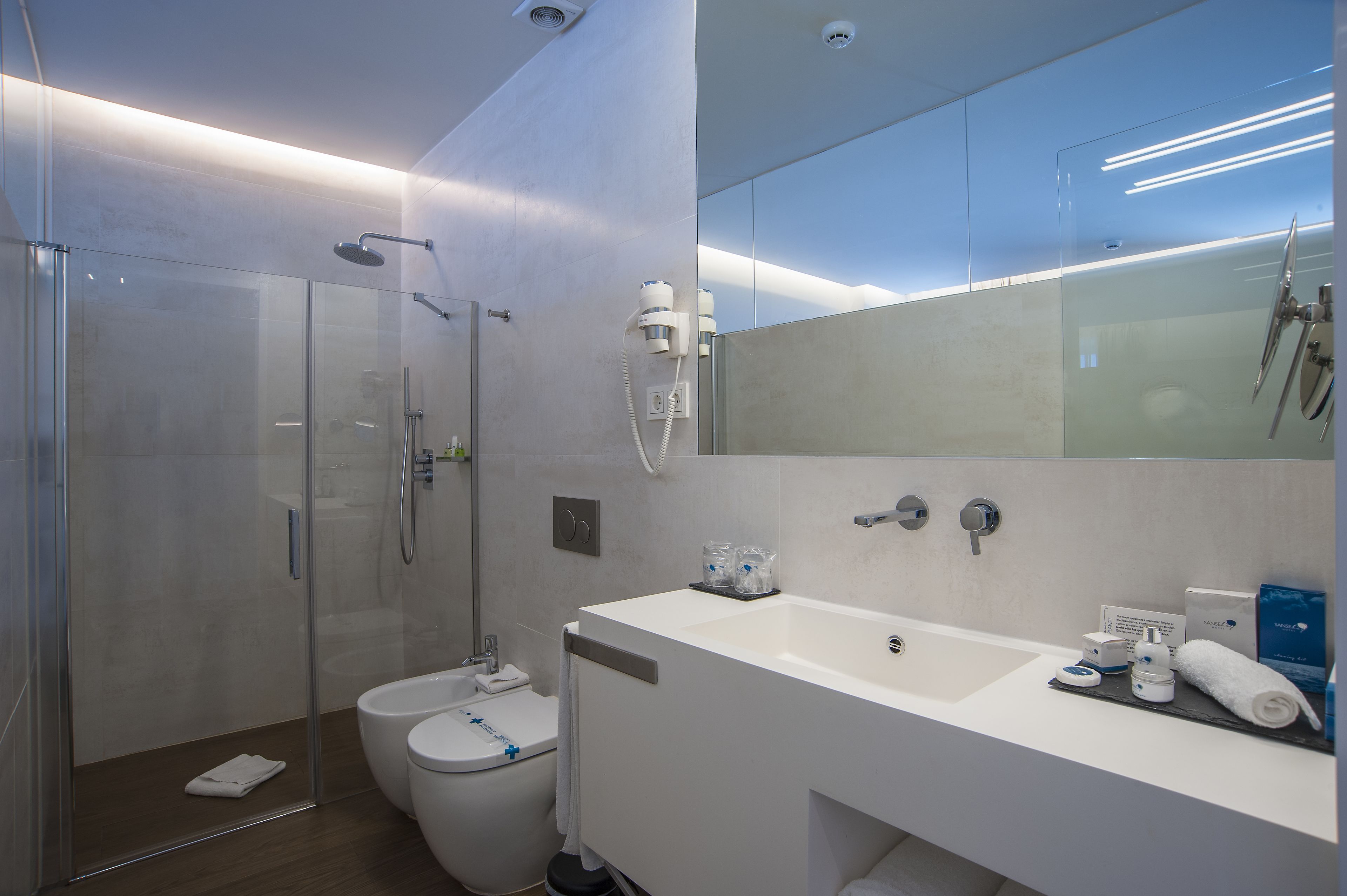 A modern bathroom with a glass-enclosed shower, a toilet, and a sink with toiletries.