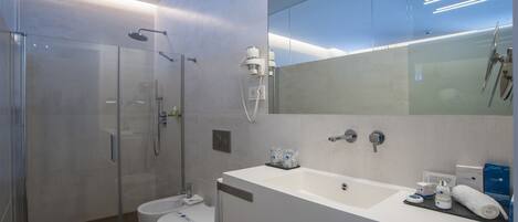 A modern bathroom with a glass-enclosed shower, a toilet, and a sink with toiletries.