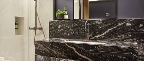 A modern bathroom with a glass-enclosed shower, a marble sink, and a large mirror.
