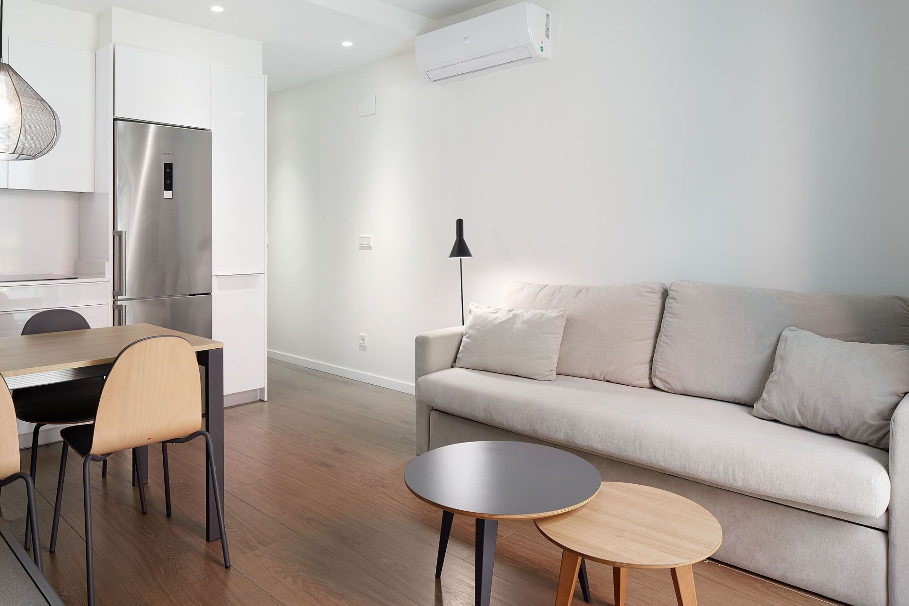 Un salon moderne avec un canapé, une table à manger et des chaises, ainsi qu’une petite table ronde.