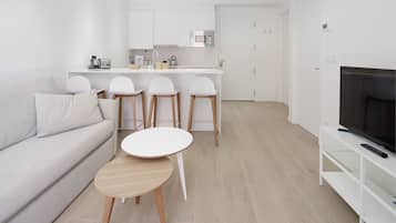 A modern living room with a sofa, a small round table, and three bar stools.