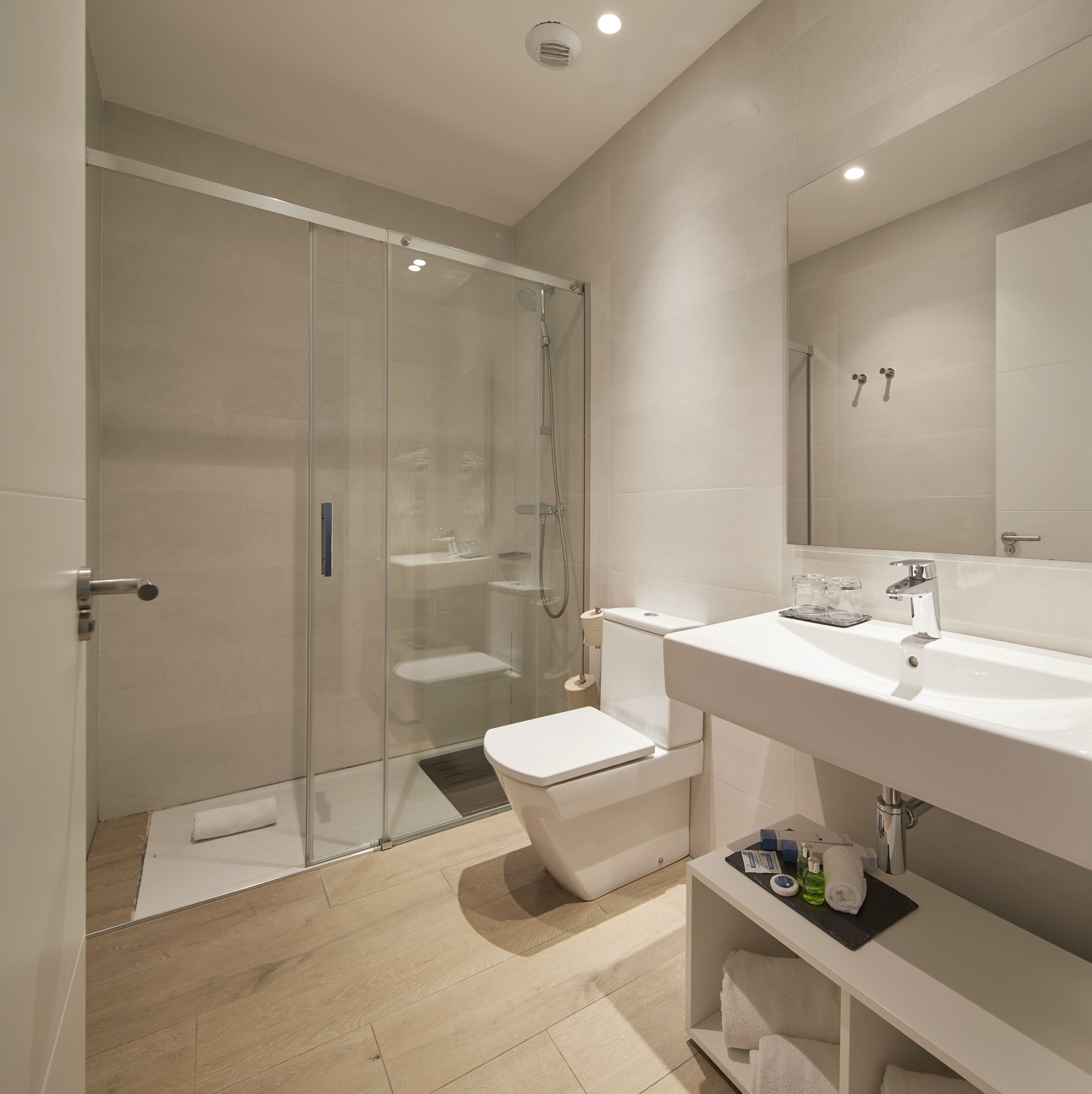 A modern bathroom with a glass-enclosed shower, a white sink, and a mirror above it.