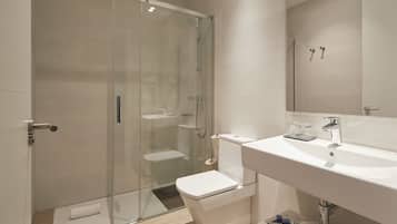Un bagno moderno con doccia vetrata, un lavandino bianco e uno specchio sopra.