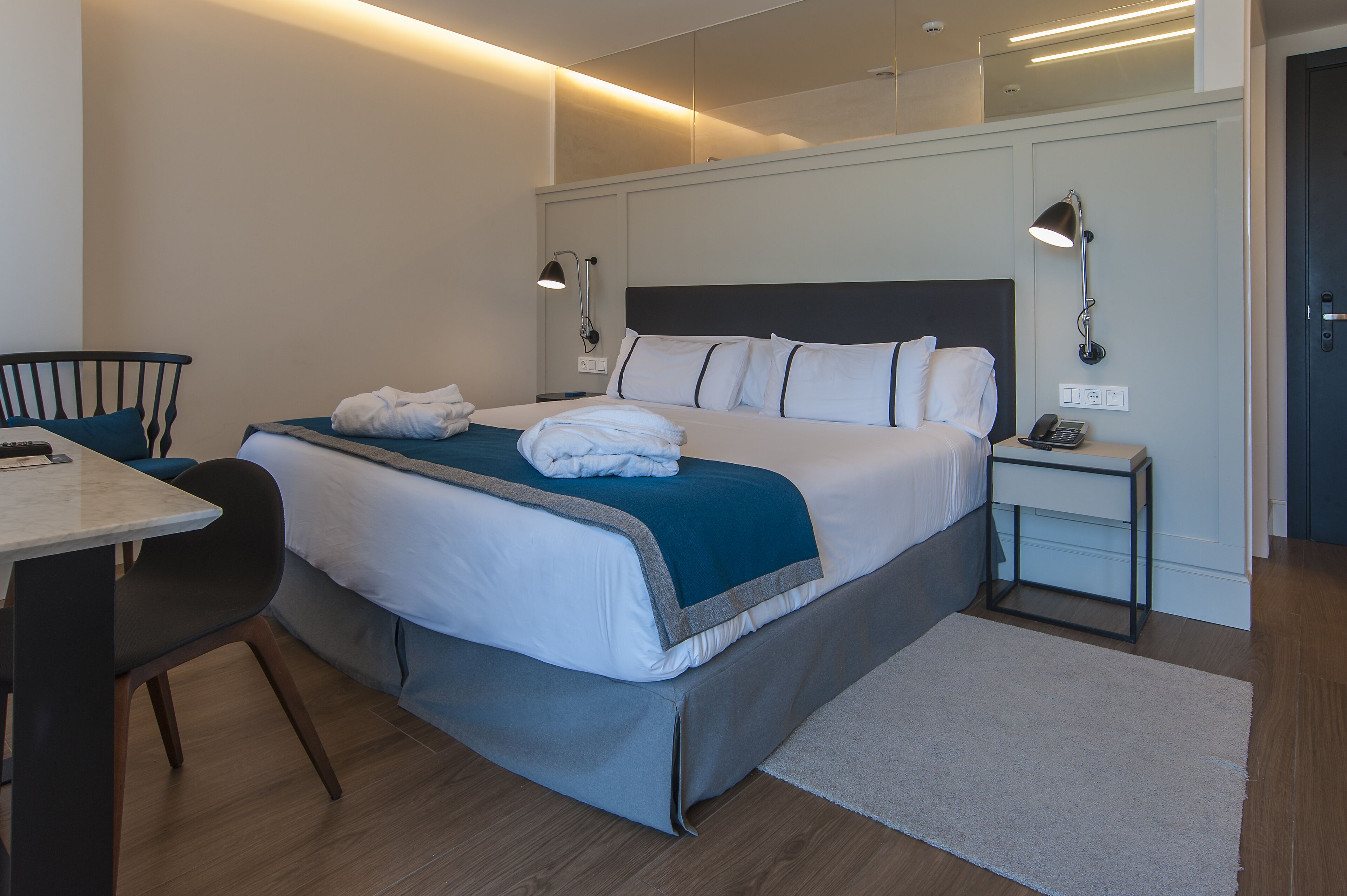 Ein Hotelzimmer mit einem großen Bett, Nachttischen, einem Schreibtisch und einem Sessel.