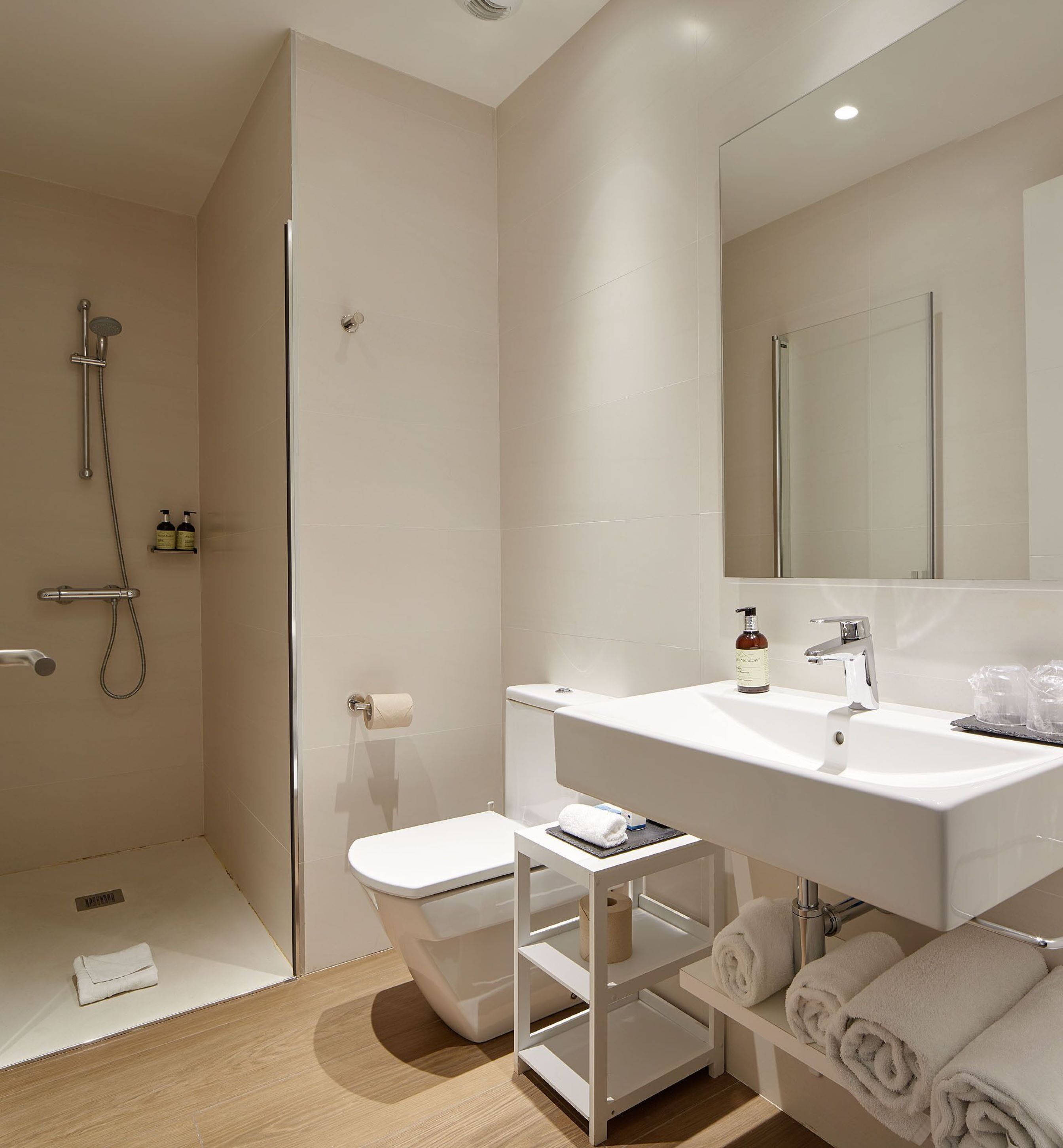 Een moderne badkamer met douche, toilet, wastafel en spiegel.