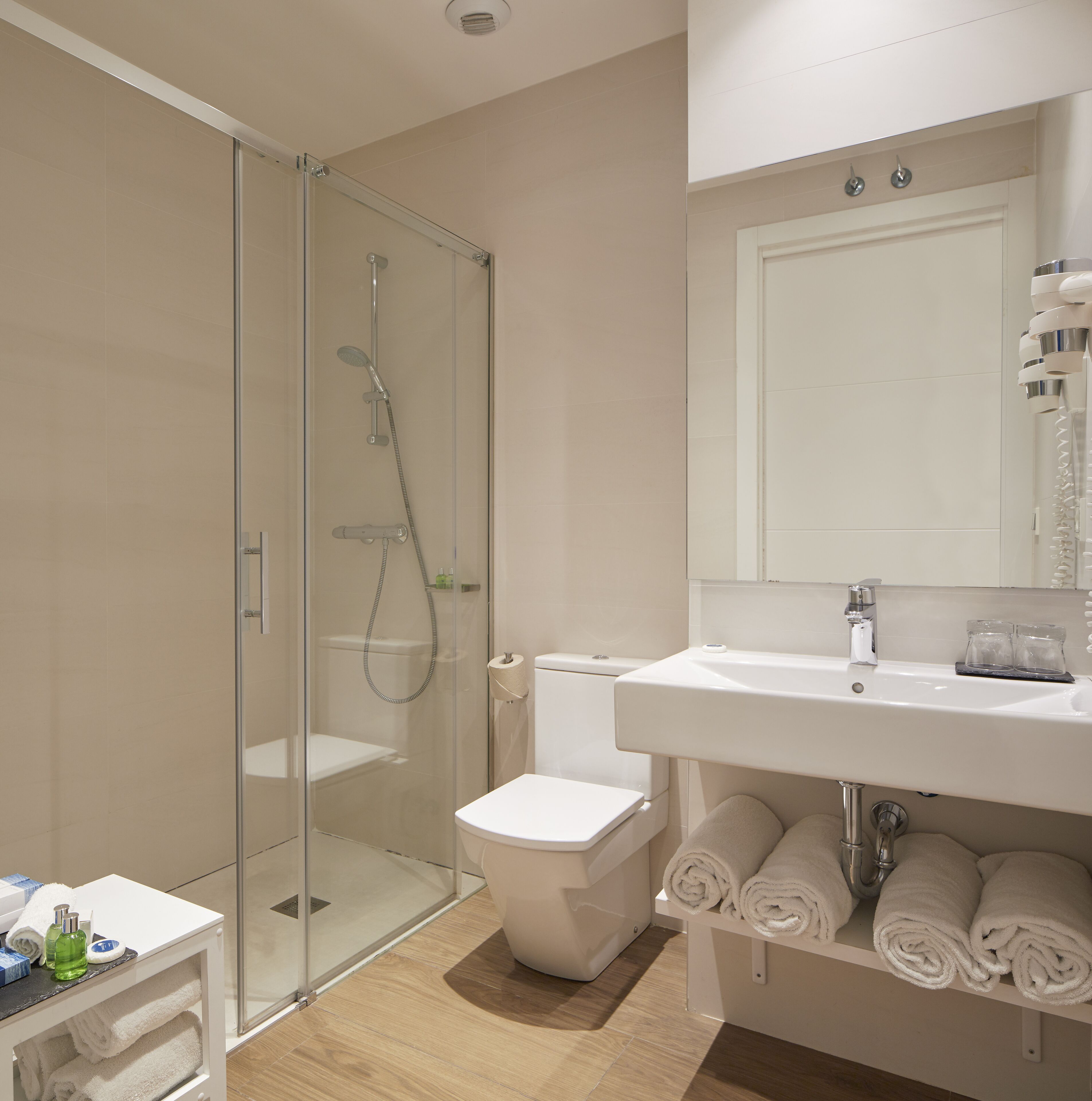 Une salle de bain moderne avec une douche à parois de verre, un lavabo blanc et un miroir au-dessus.