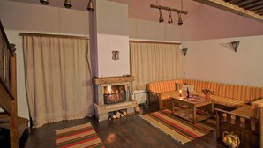 A cozy living room with a fireplace, striped rugs, and a striped sofa. - Holiday Village Kochorite (Smolyan)