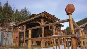 A rustic wooden cabin with a sloped roof, surrounded by snow and trees. - Holiday Village Kochorite (Smolyan)
