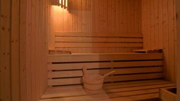 A wooden sauna with benches and a wooden bucket.