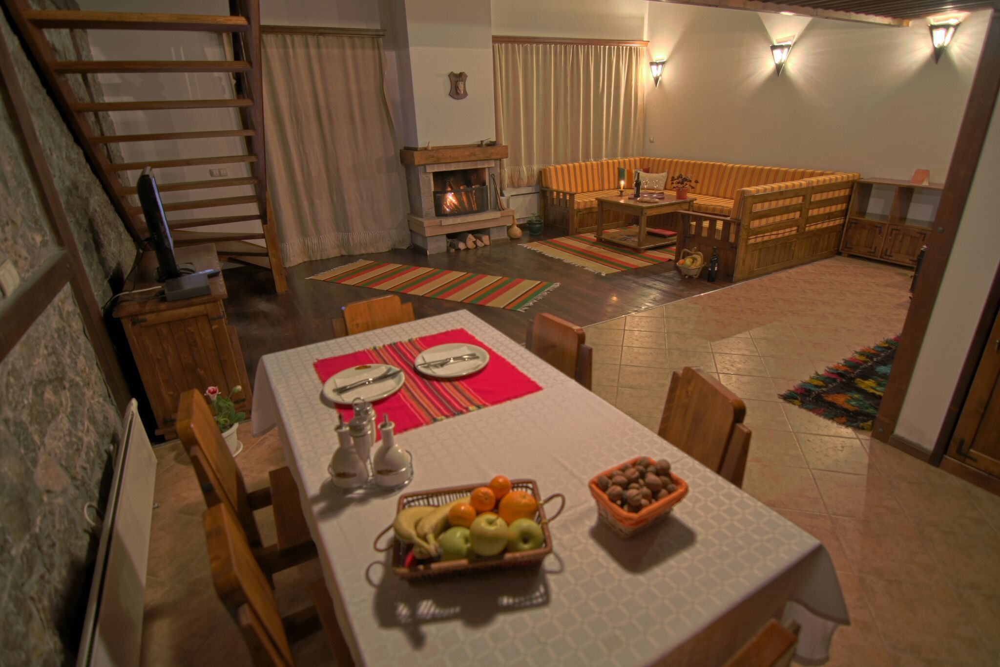 Ein Essbereich mit Tisch für zwei, Kamin und einer gemütlichen Sitzecke mit Sofa und Bank.
