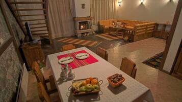 Ein Essbereich mit Tisch für zwei, Kamin und einer gemütlichen Sitzecke mit Sofa und Bank.