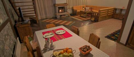 Un área de comedor con una mesa dispuesta para dos personas, una chimenea y un rincón de estar acogedor con un sofá y un banco.