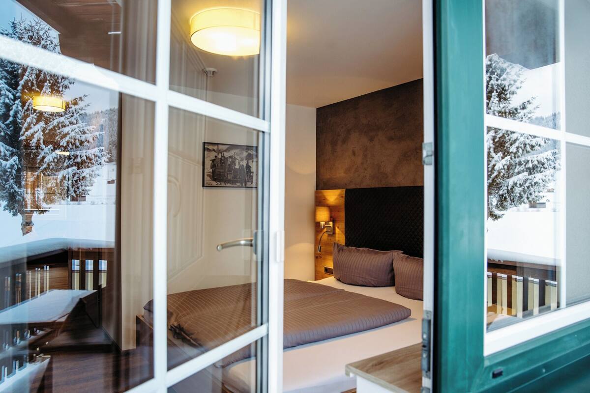 A modern hotel room with a large bed, a bedside table, a lamp, and a framed picture on the wall.