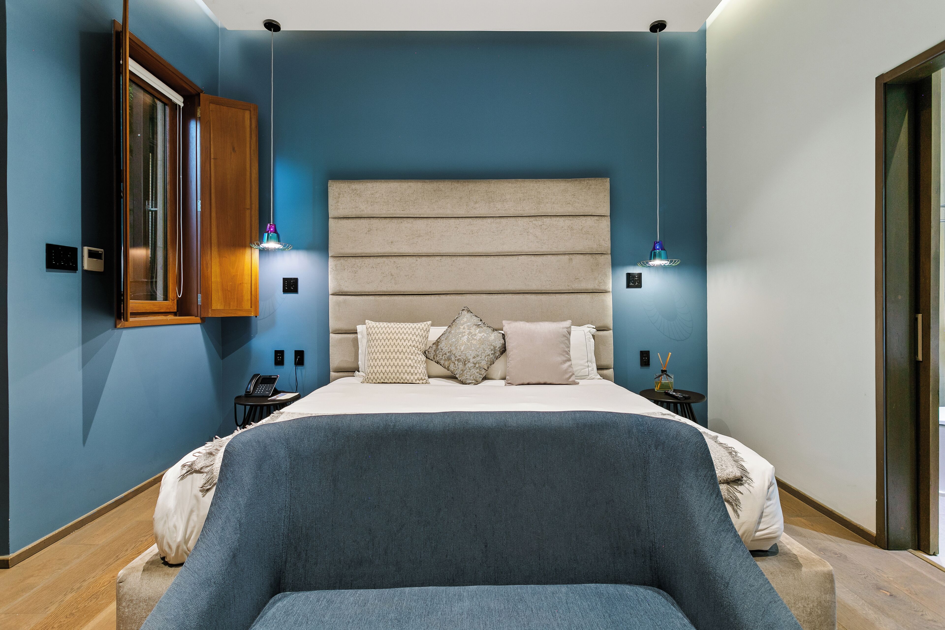 Un dormitorio con cama, mesitas de noche, una silla y un armario.