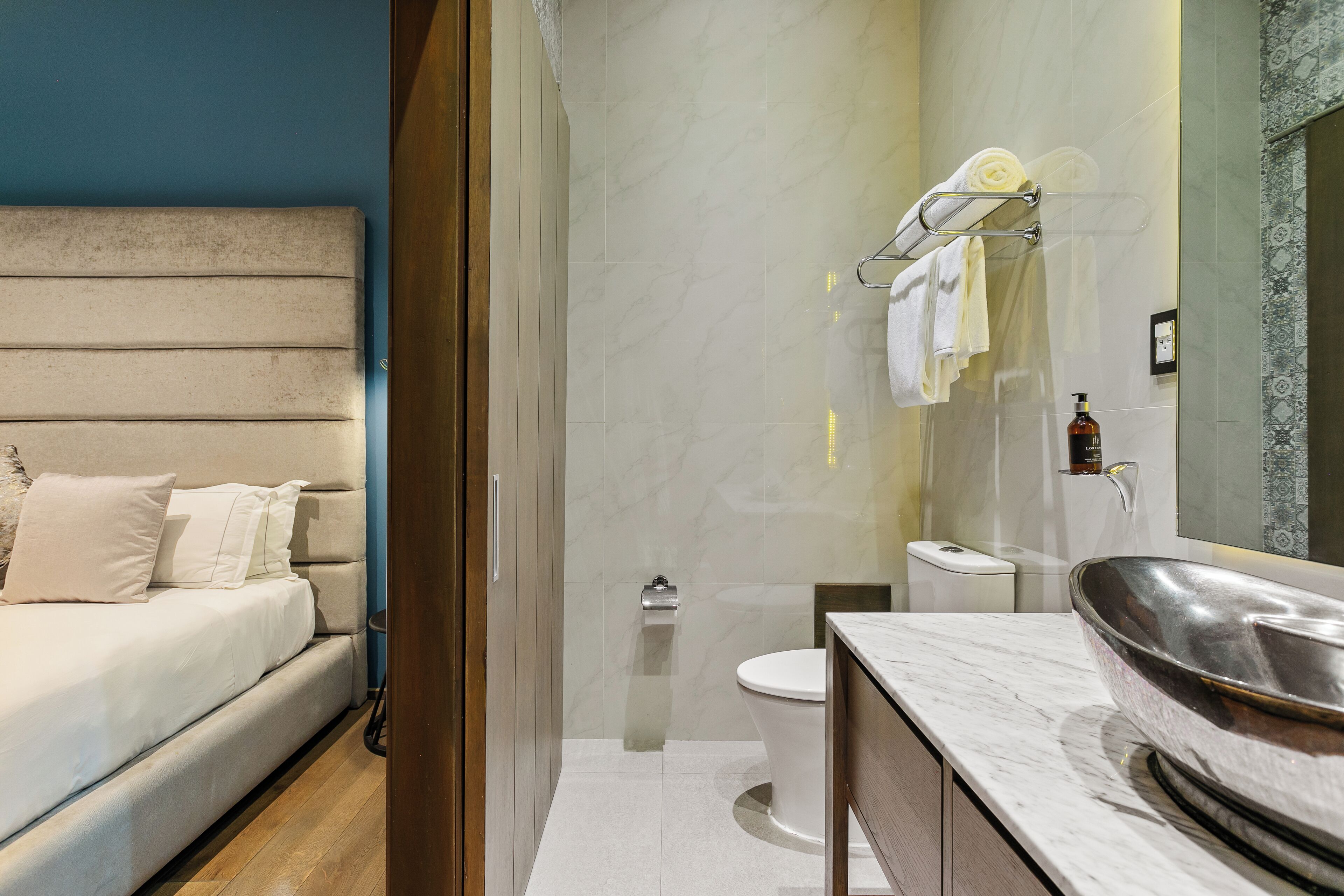 A modern bathroom with a large mirror, a toilet, and a sink.