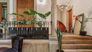 Un hall d’entrée avec un escalier, une porte en bois et des plantes en pot.