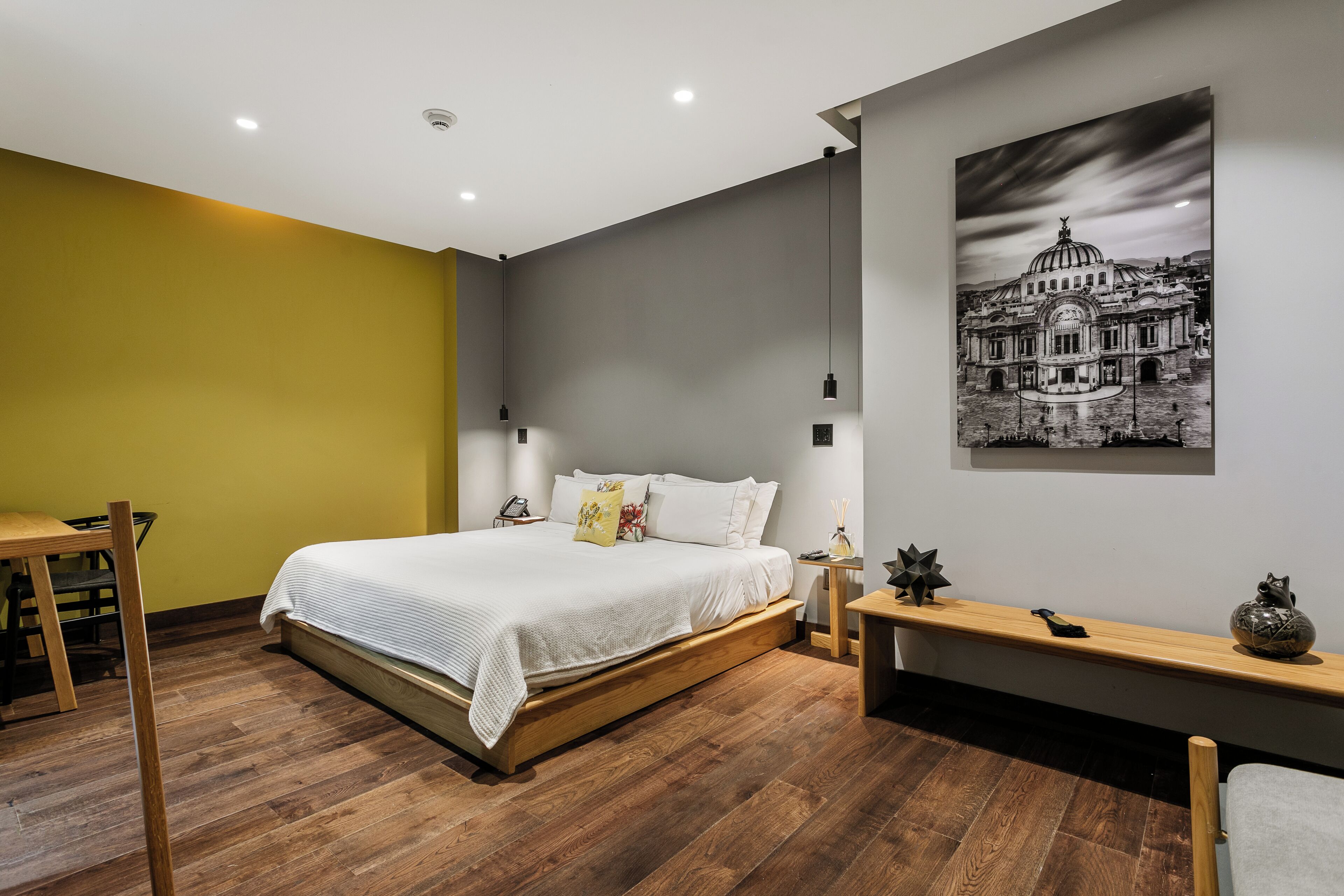 Un dormitorio moderno con cama, mesita de noche, lámpara y un cuadro colgado en la pared.
