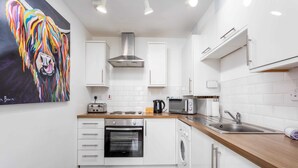 Eine moderne Küche mit weißen Schränken, einer Edelstahl-Dunstabzugshaube, einer Mikrowelle, einem Toaster und einem Spülbecken.