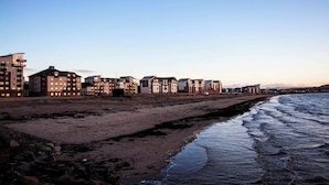 Ein Küstenhotel mit mehreren Gebäuden direkt am Strand, mit Sandstrand und Wellen.
