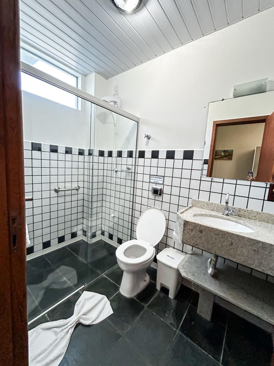 Une salle de bain moderne avec une douche à l’italienne en verre, des toilettes blanches, un lavabo avec un plan de travail en marbre et un sol carrelé.