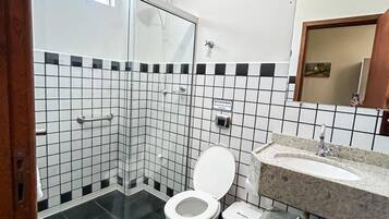 Une salle de bain moderne avec une douche à l’italienne en verre, des toilettes blanches, un lavabo avec un plan de travail en marbre et un sol carrelé.