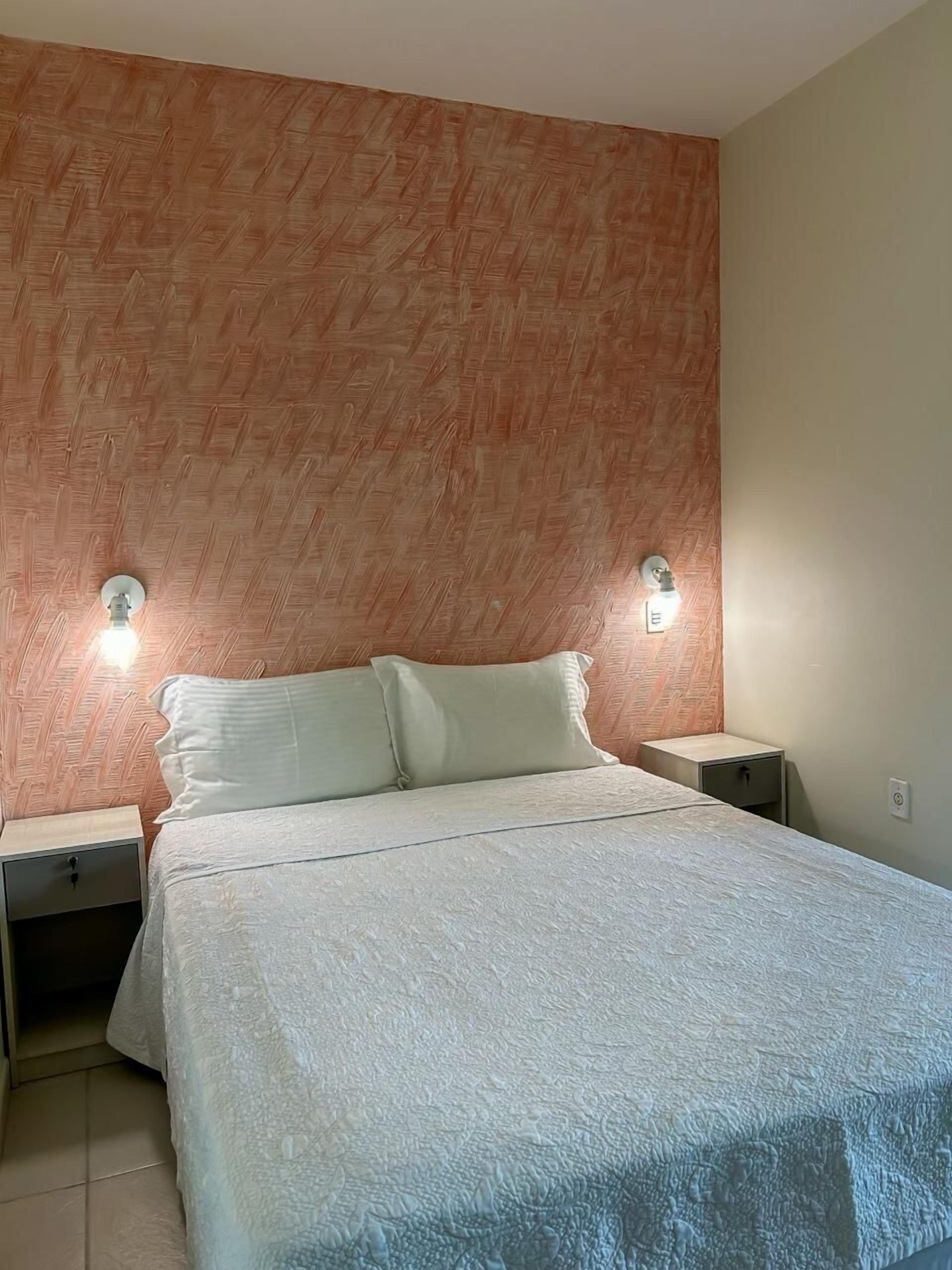 Un dormitorio con una cama, dos mesitas de noche y una pared con diseño de espiga.