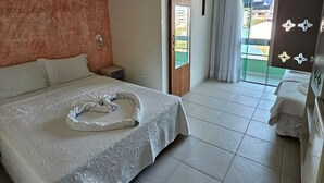 Une chambre d’hôtel avec un grand lit, une petite table de chevet, une porte en bois et une vue sur l’extérieur.