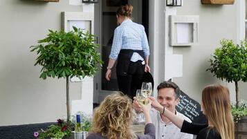 Un restaurante llamado "The Fleece" con terraza y cestas decorativas de flores.