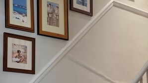 A staircase with bookshelves on the side, framed pictures on the wall, and a white handrail. - The Fleece (Witney)