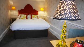Une chambre d’hôtel avec un lit, deux lampes de chevet, une table de chevet avec une lampe et une tasse rouge.
