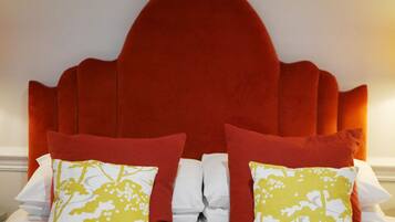 A bed with a red upholstered headboard, white bedding, and two decorative pillows with yellow floral patterns.