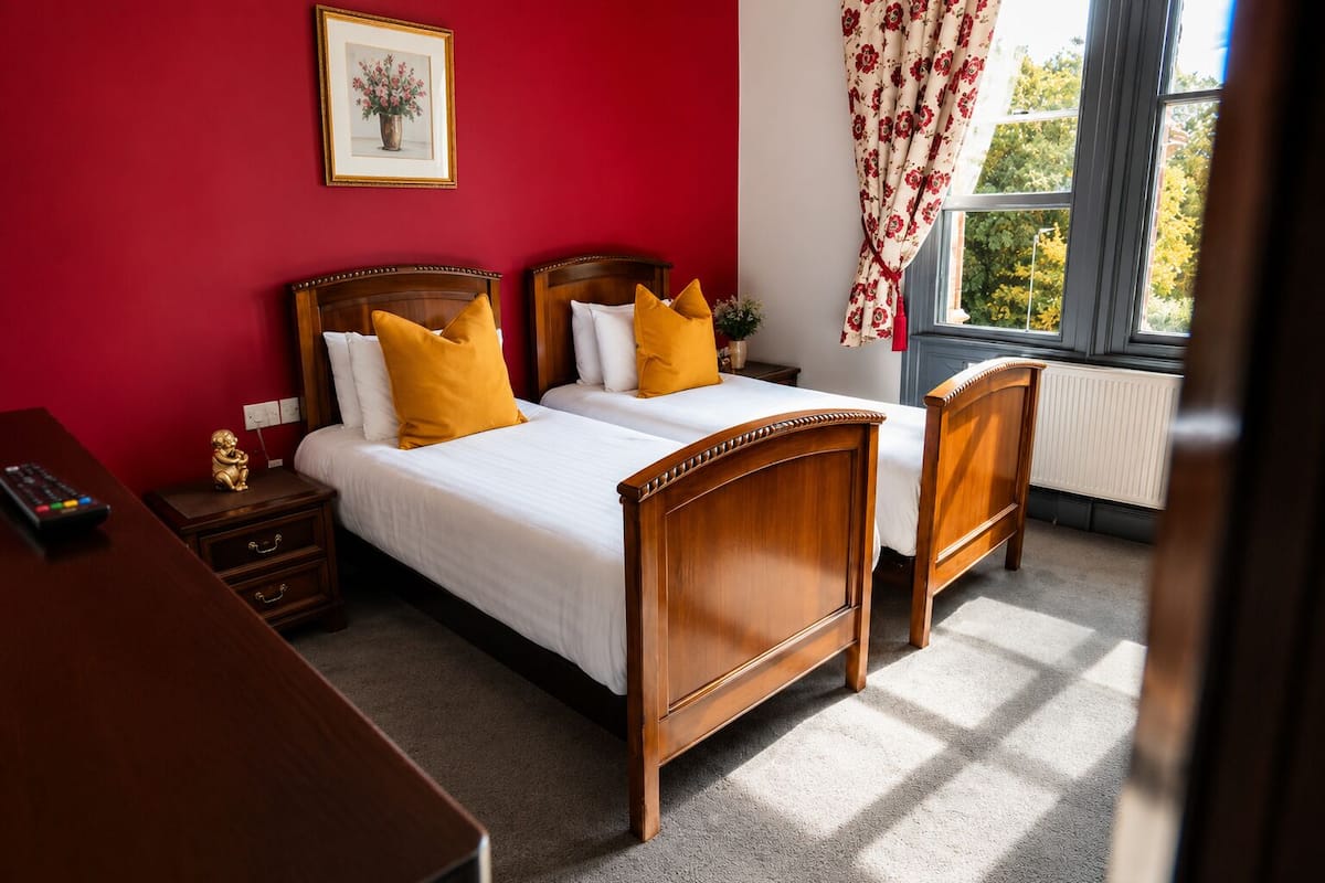 A double bed with wooden headboards, a nightstand with a remote control, and a framed picture on the wall.