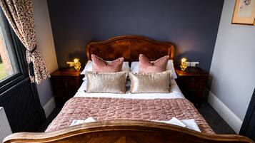 Una camera da letto con testiera in legno, un letto con biancheria rosa, due comodini con lampade e una finestra con tende.