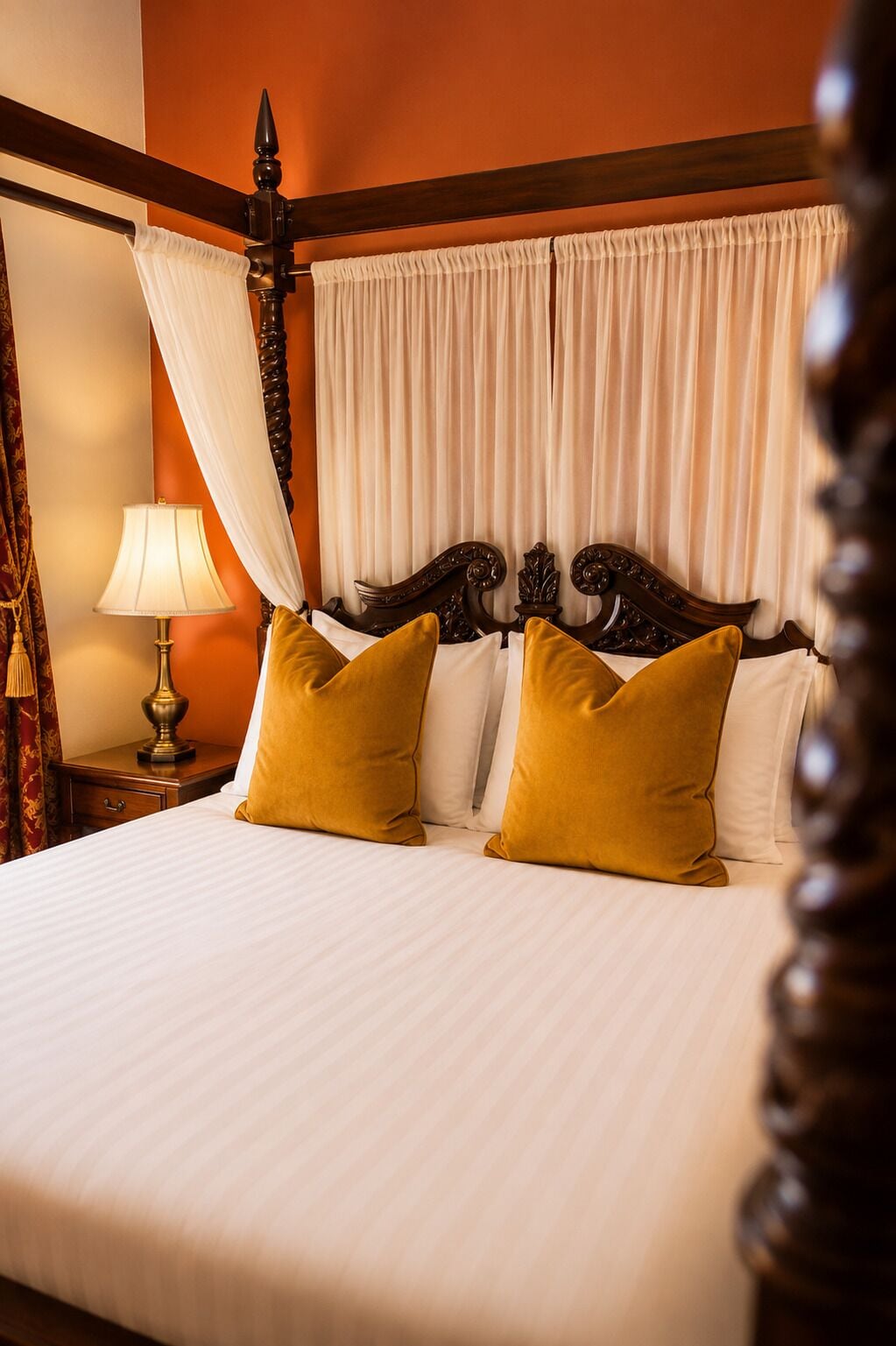 A bed with white linens, two mustard pillows, a wooden headboard, and a nightstand with a lamp.