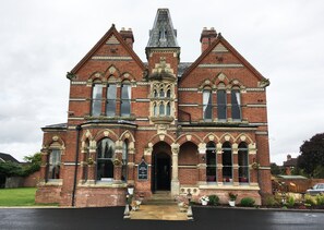 A large, historic building with a prominent central tower, multiple arched windows, and a symmetrical facade. - The Godwins (Hereford)