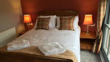 Un lit bien fait, avec deux oreillers, deux lampes de chevet et une serviette pliée posée sur le pied de lit.