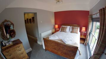 A bedroom with a wooden bed, two bedside lamps, a mirror, and a dresser.