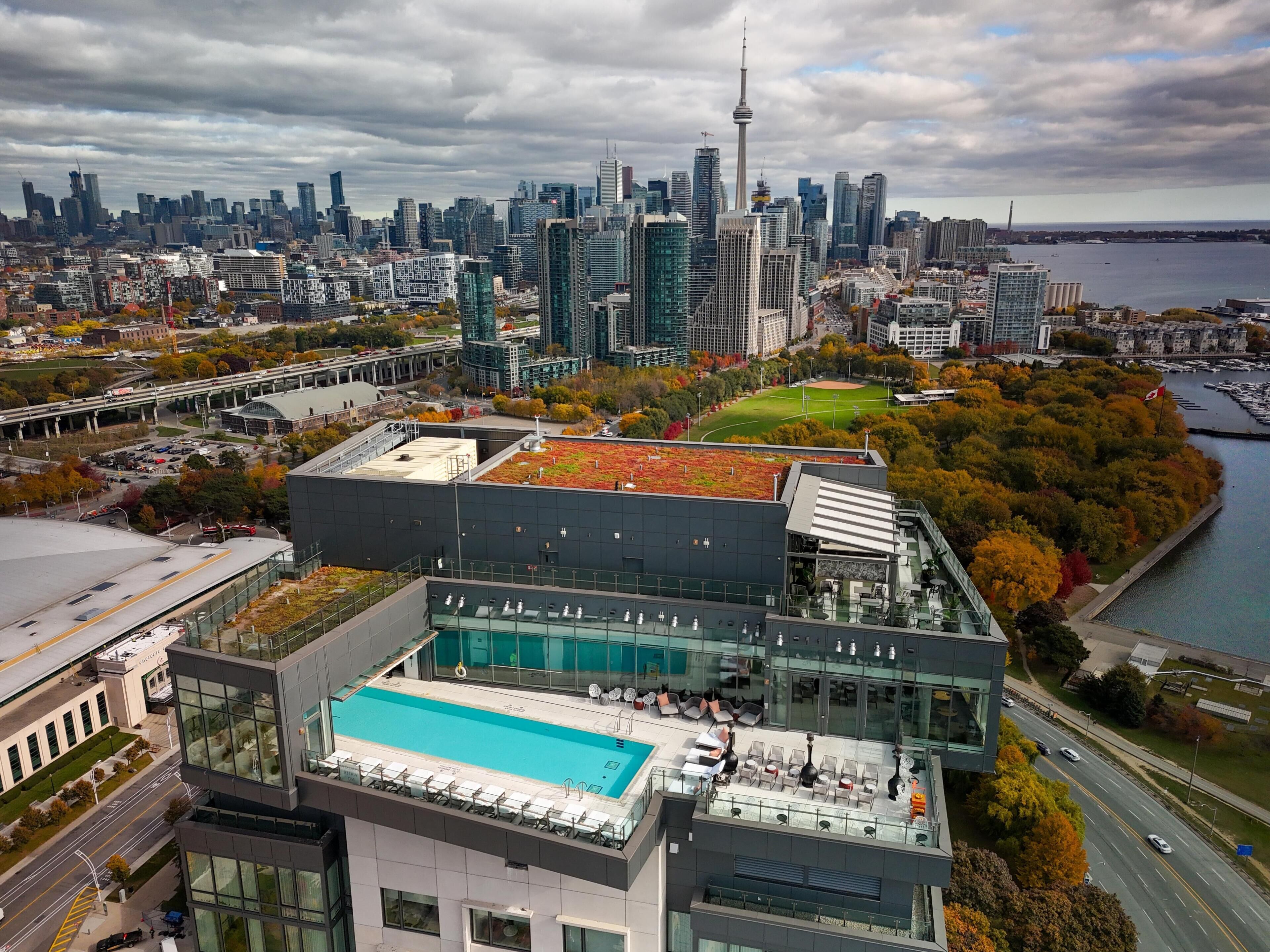 A modern building with a rooftop pool, a view of the city skyline, and a waterfront.
