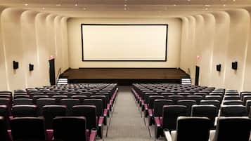 Un teatro con hileras de asientos frente a una pantalla grande.