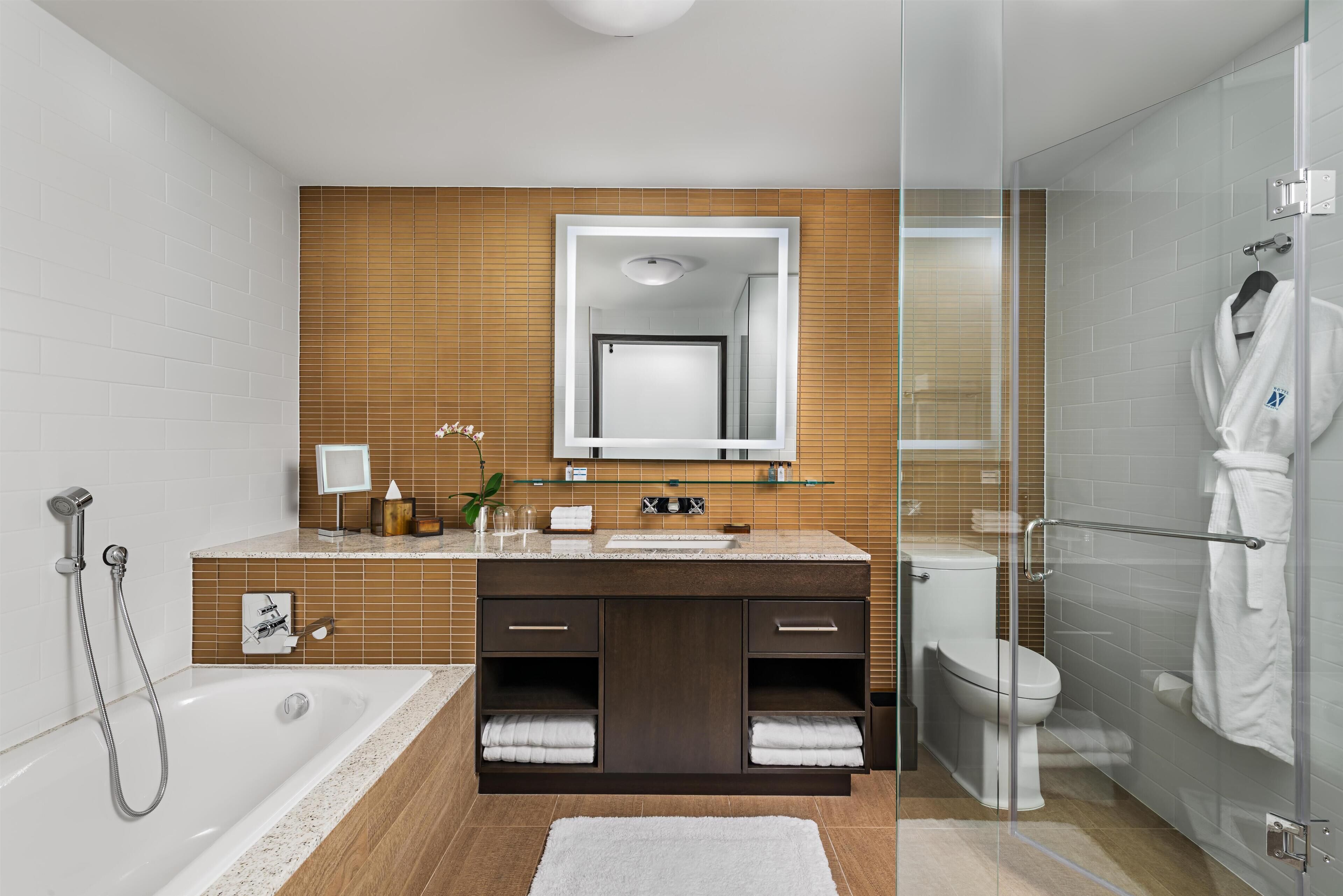 Een moderne badkamer met een douchecabine van glas, een badkuip, toilet en een wastafel met spiegel.