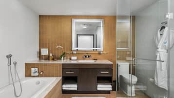 Een moderne badkamer met een douchecabine van glas, een badkuip, toilet en een wastafel met spiegel.